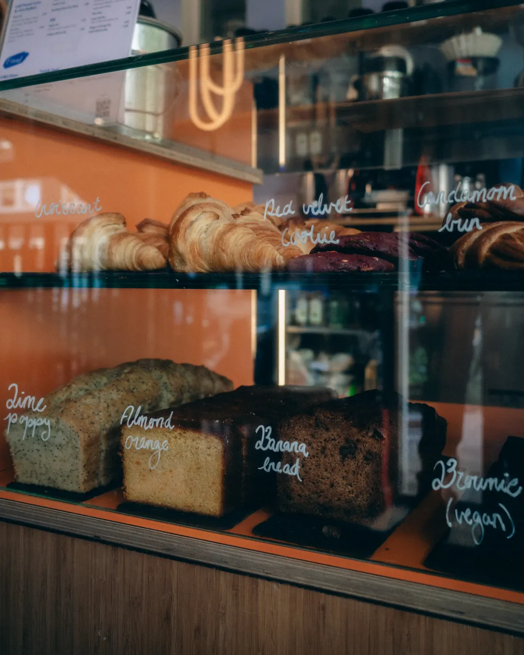 Pastry counter with croissants, banana bread and cakes at Caffènation by Guji on Warmondstraat