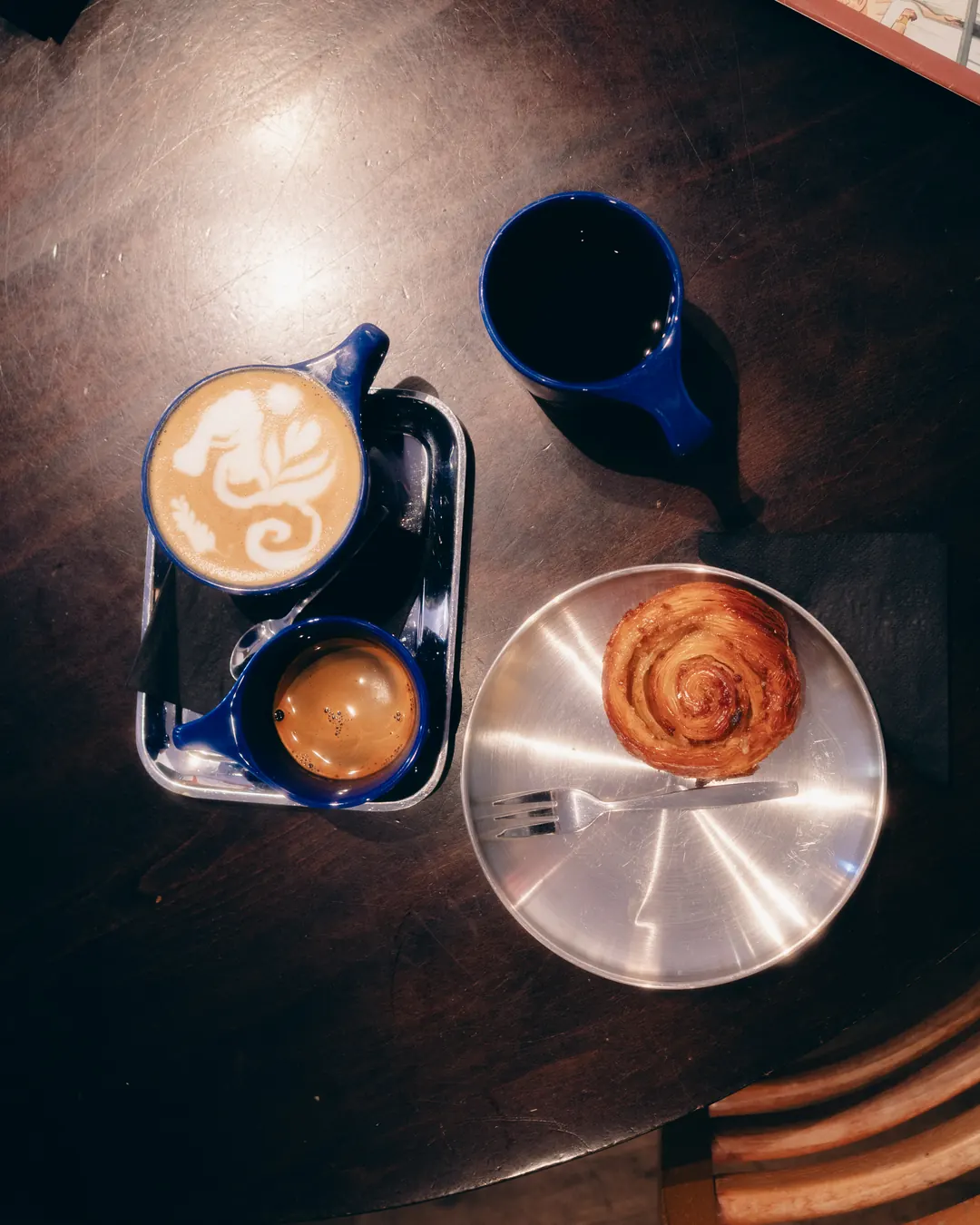 Cappuccino, cortado and a cinnamon bun on a tray