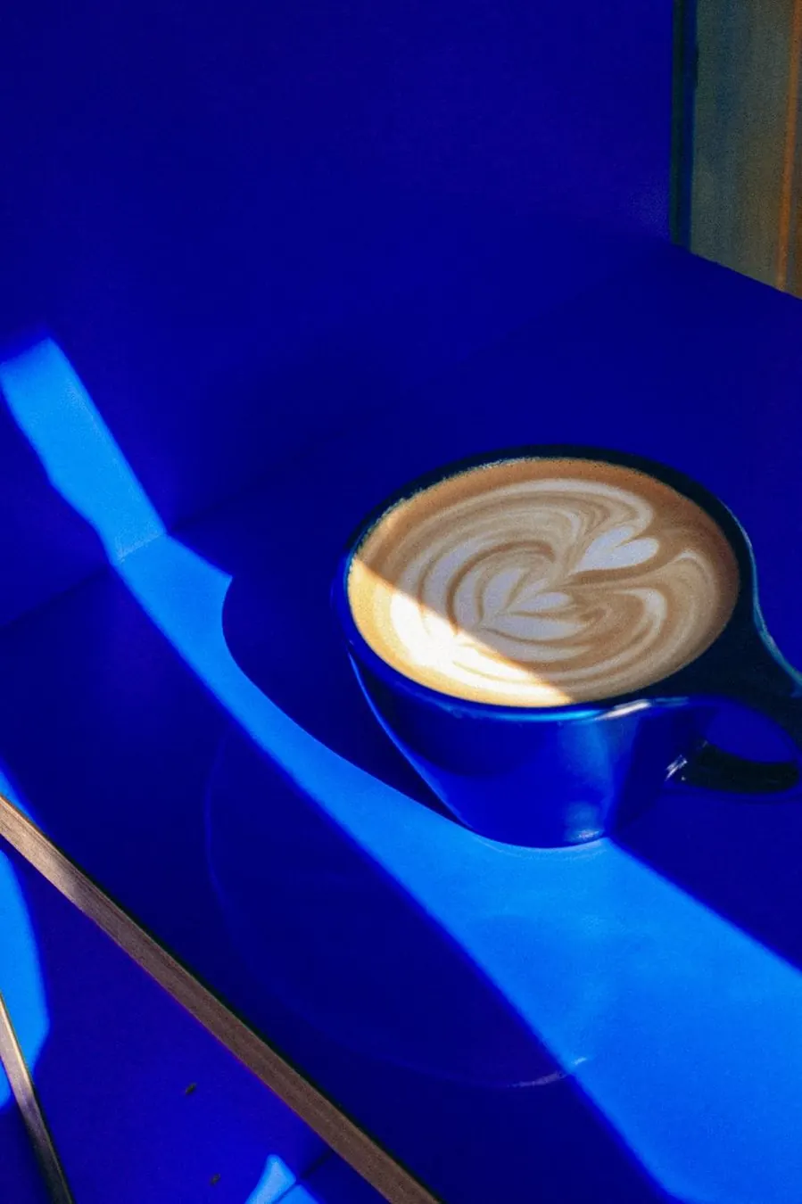 Latte art in a blue cup against the blue of the kiosk